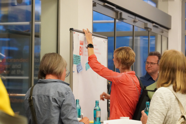 Menschen arbeiten an einer Pinnwand