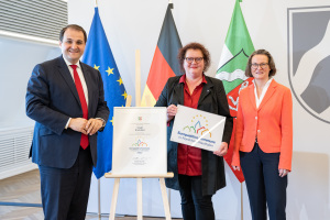 Bürgermeisterin Christina Osei (Mitte) nimmt die Auszeichnung von Nathanael Liminski, Minister für Bundes- und Europaangelegenheiten, Internationales sowie Medien, und Ina Scharrenbach, Ministerin für Heimat, Kommunales, Bau und Digitalisierung des Landes Nordrhein-Westfalen, entgegen.